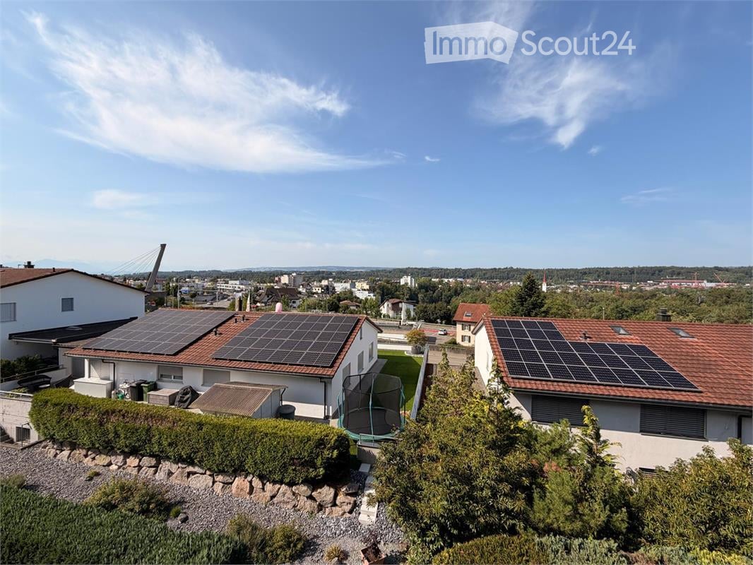 Aerial view of a residential area with multiple houses, solar panels on roofs, and a trampoline in the yard.