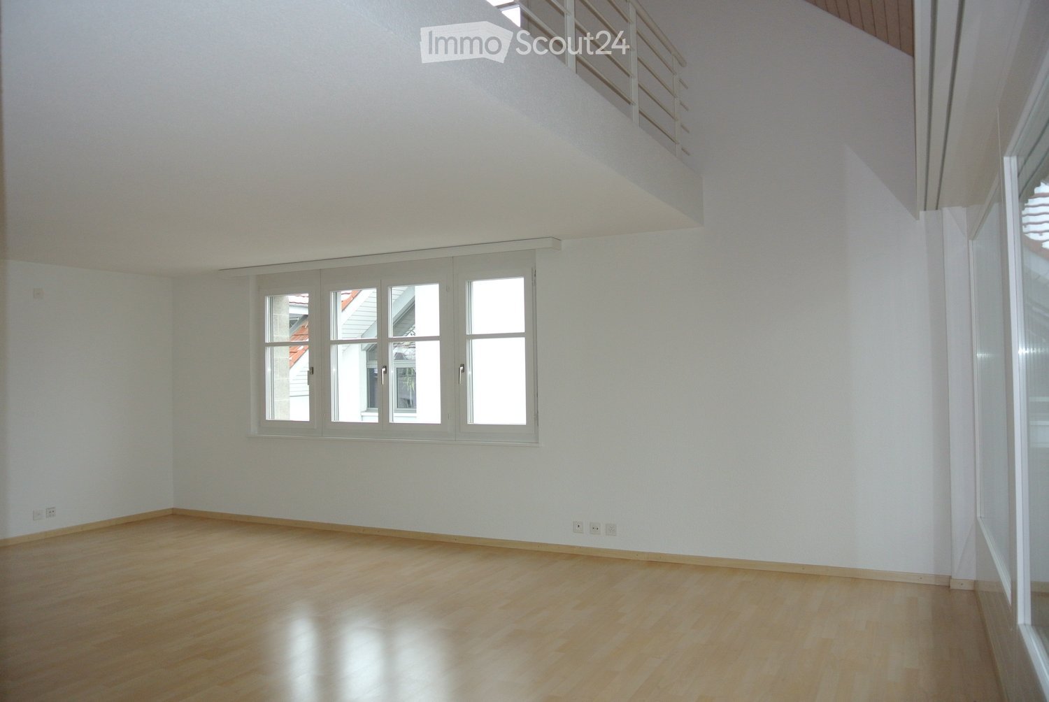 Empty room with light wooden flooring, white walls, and large windows allowing natural light. No furniture or equipment is present.