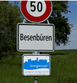 Road sign displaying speed limit of 50 km/h and the name "Besenbüren" along with an energy award sign.