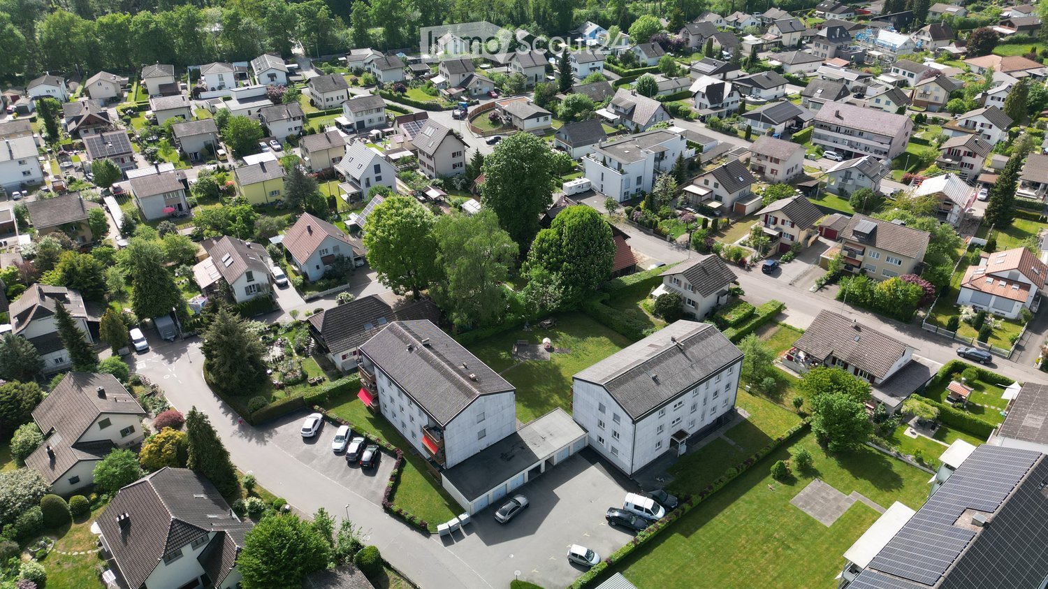 Aerial view of a residential neighborhood with multiple houses, garages, and parked cars.