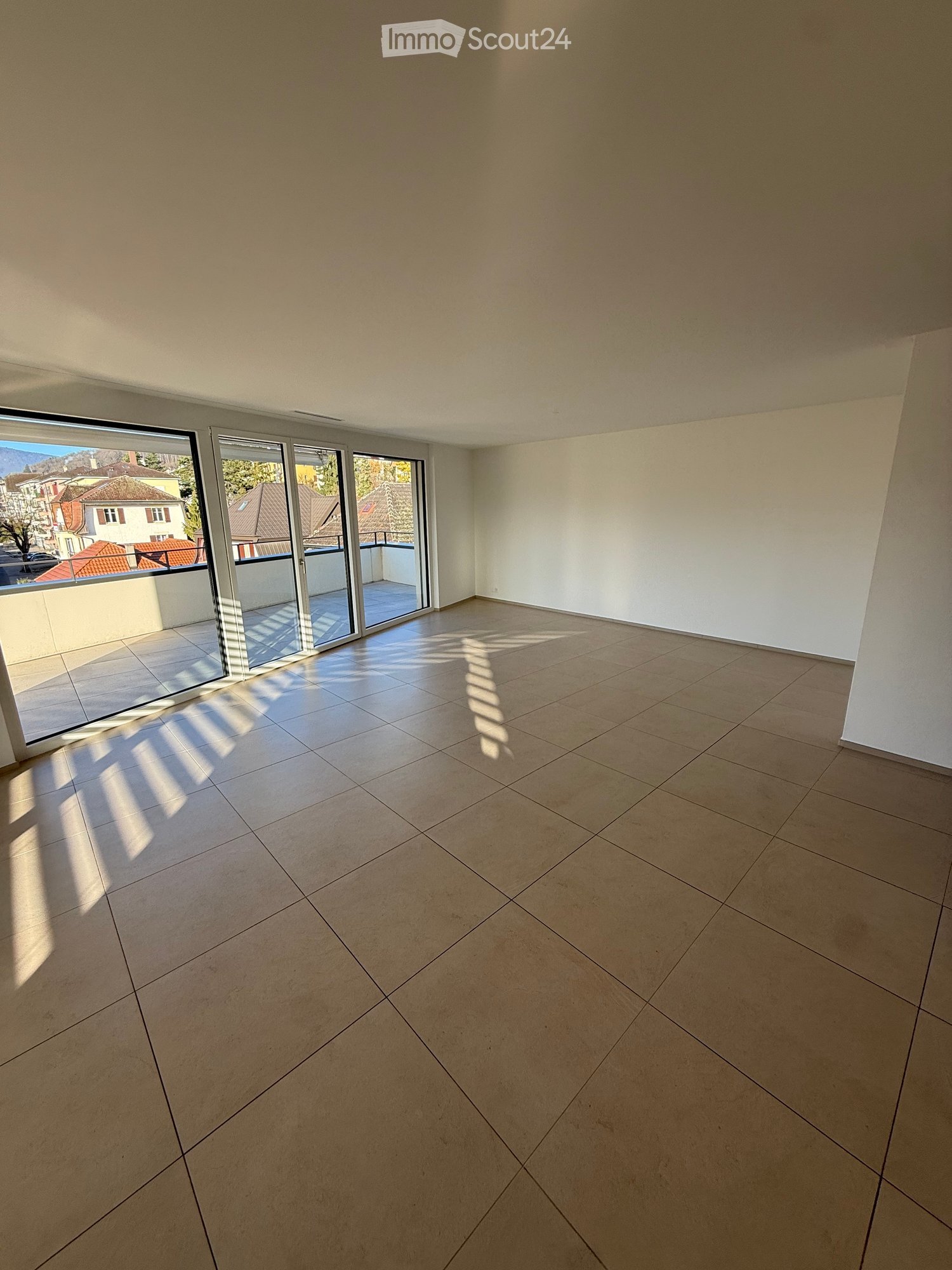 Empty room with tiled floor and large sliding glass doors leading to a balcony.