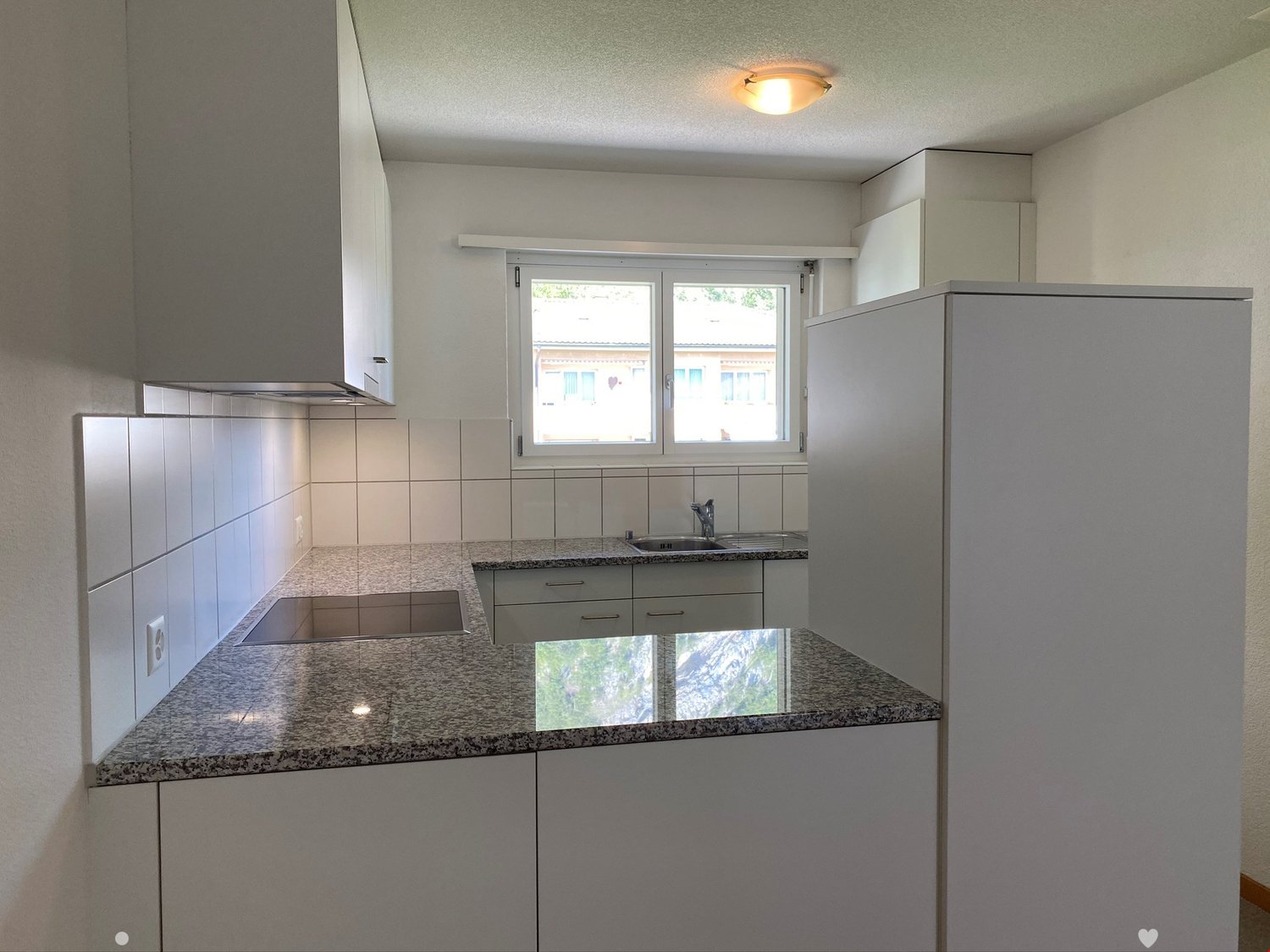 Modern kitchen with granite countertops, white cabinets, stainless steel sink, and a built-in refrigerator.