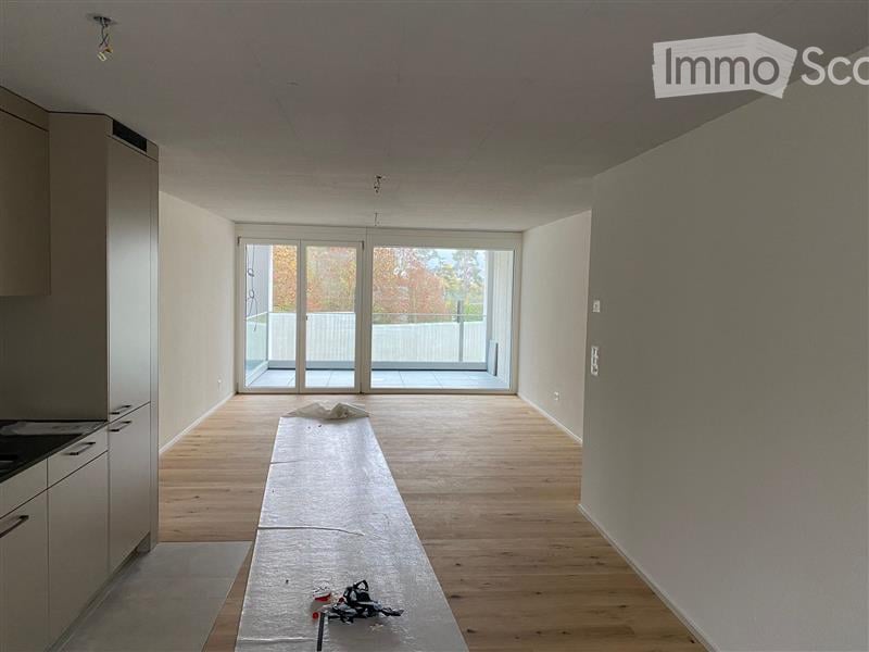 Empty room with wooden flooring, white walls, and large sliding glass doors leading to a balcony or terrace area.