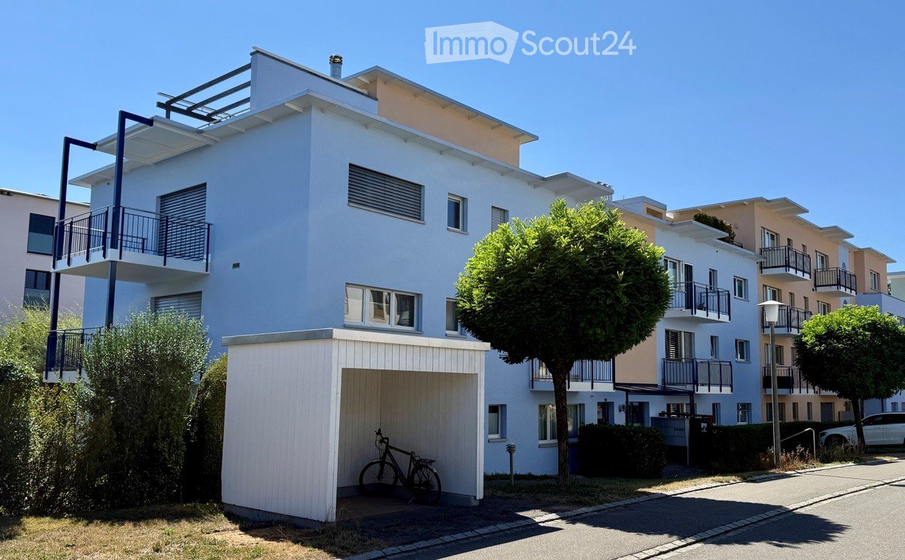 Modern two-story apartment building with white exterior, balconies, and a garage with a bicycle inside.