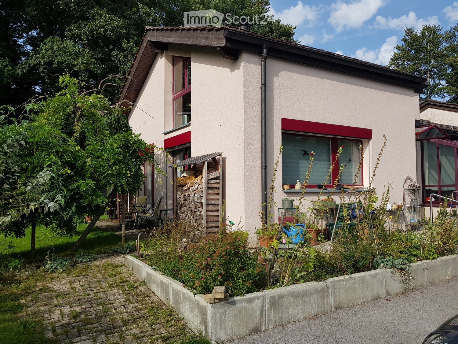 2 story house, white walls, red trim, brick pathway, garden, wood storage, outdoor seating
