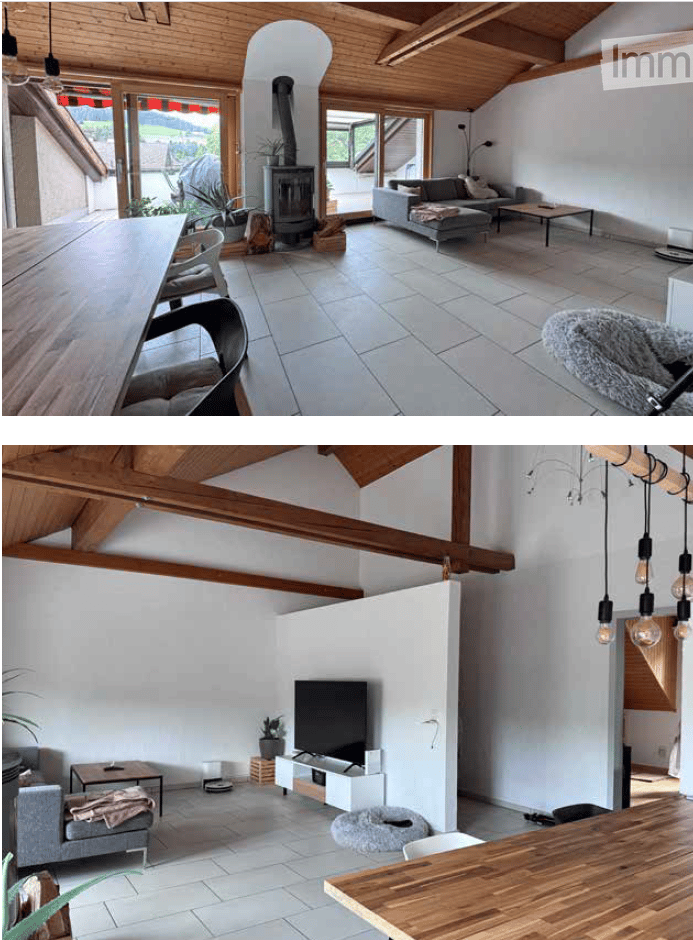 Open-plan living and dining area with exposed wooden beams, fireplace, grey sofa, coffee table, dining table with chairs, and television area with a flat-screen TV and floor lamp.