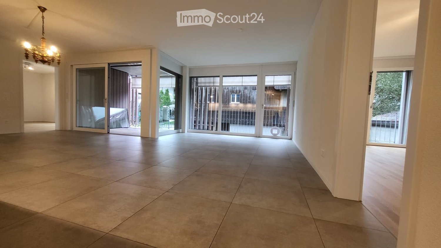 tiled floor, chandelier, three large windows, three glass doors leading to balcony