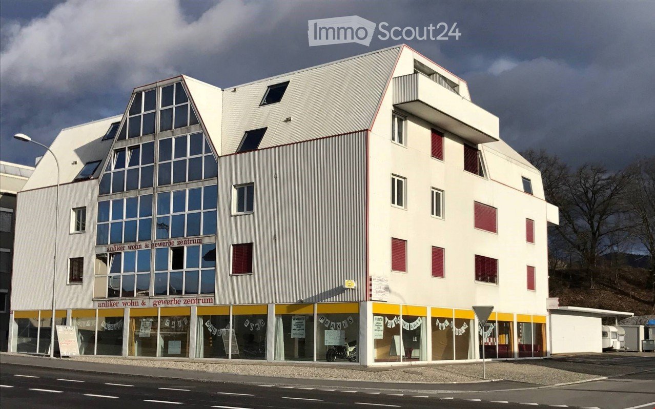 Modern building with glass windows, red shutters, yellow and white exterior, street light, signboards, and a motorcycle parked in front.