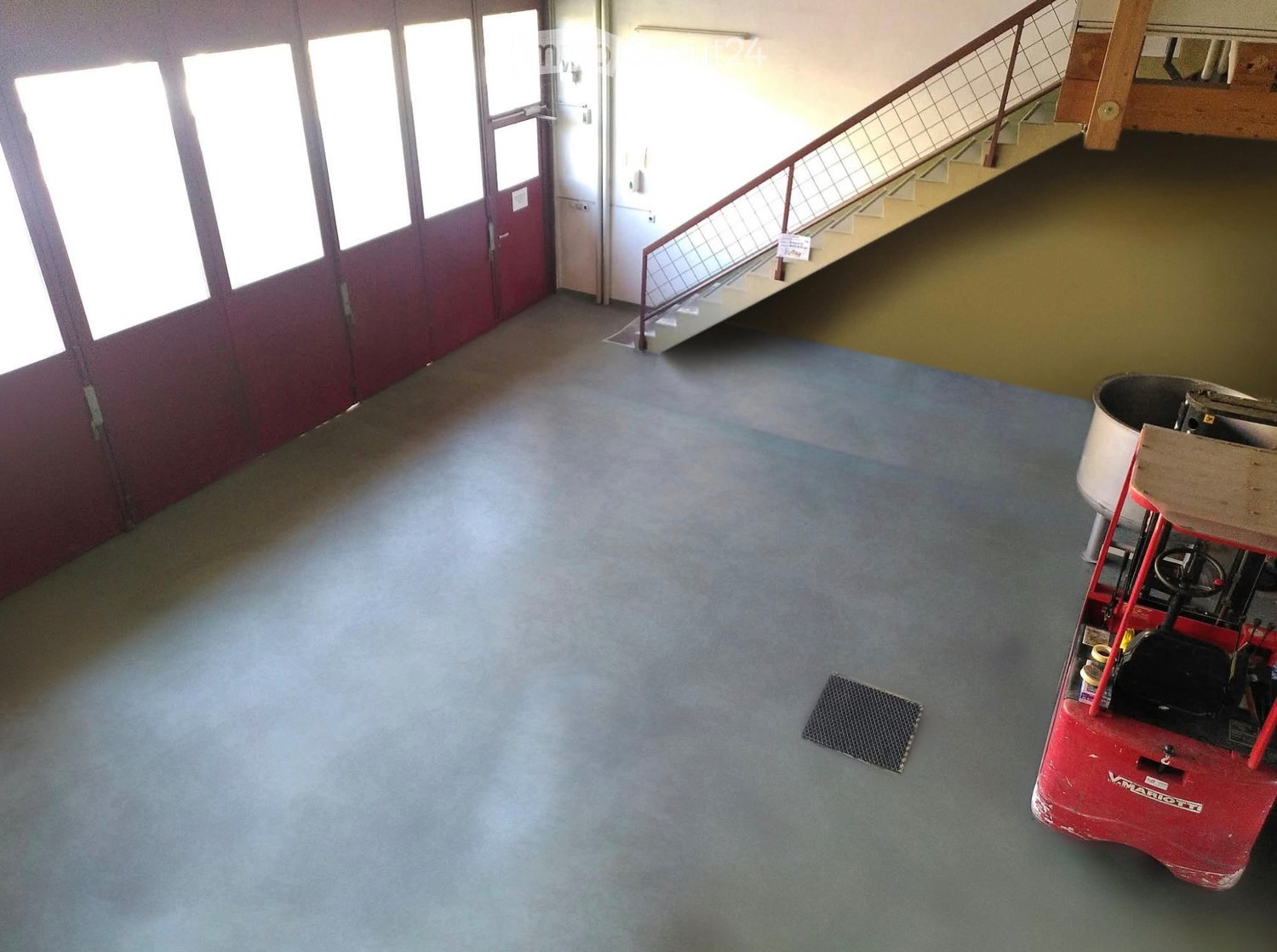 Empty room with grey carpeted floor, large windows, staircase leading to an upper level, and a red floor scrubber in the corner.