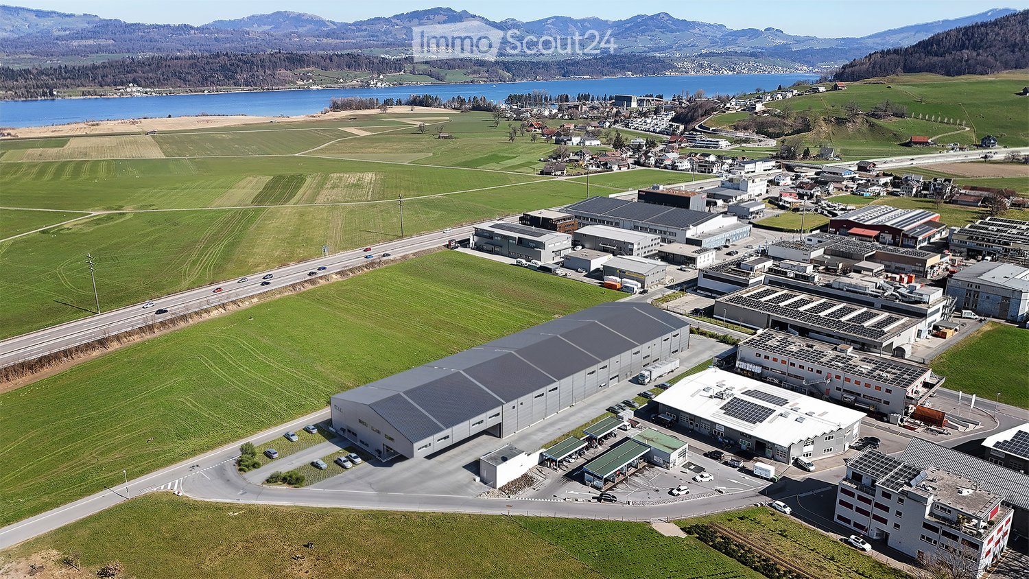 Large industrial building with several solar panels on the roof and a wide parking lot.