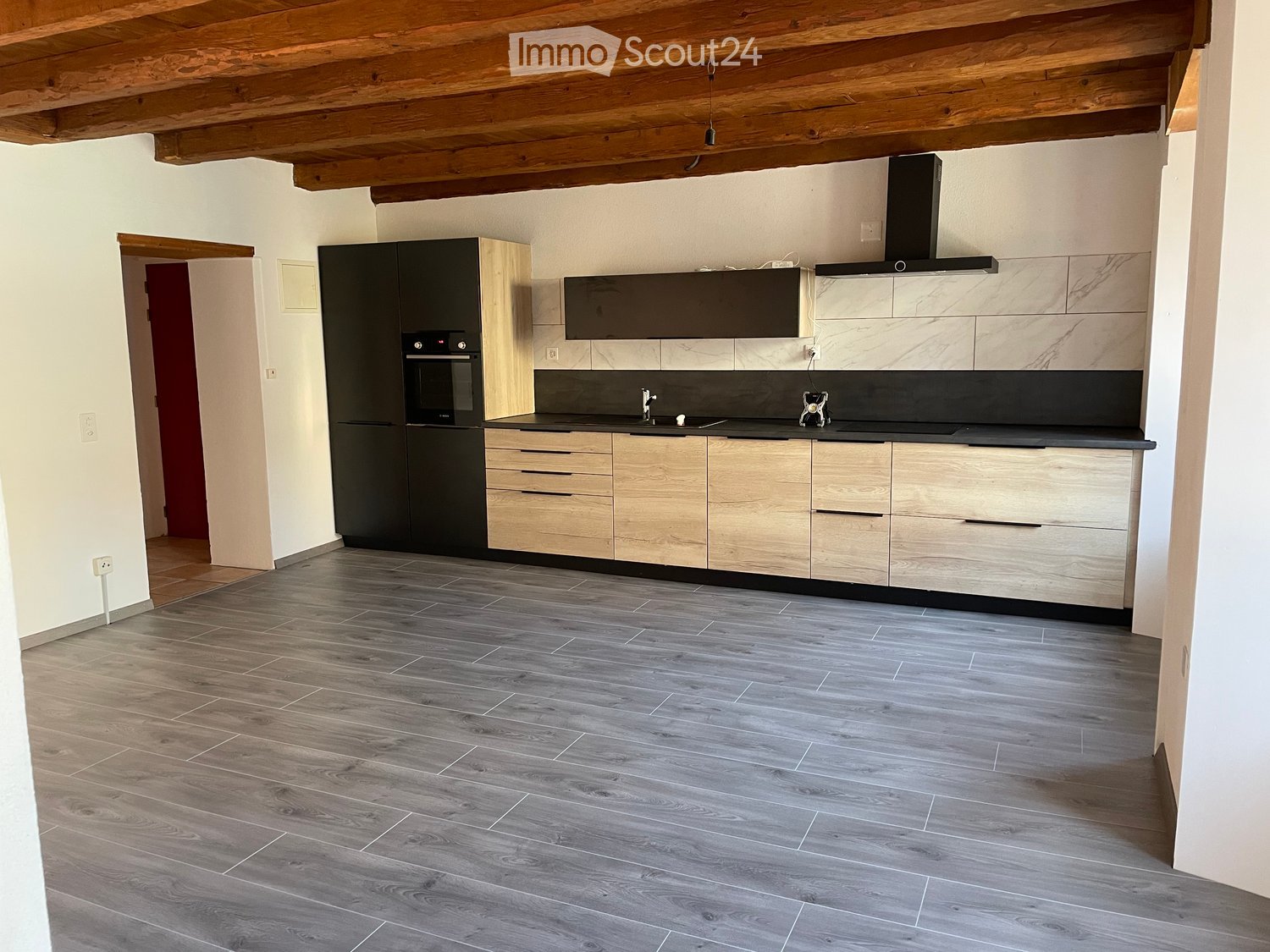 Modern kitchen with wooden cabinets, stainless steel appliances, and a dark countertop. Features include a refrigerator, oven, sink, and faucet.