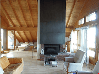 Bright living room with wooden beams, large windows, fireplace, sofa, armchair, coffee table, side table.