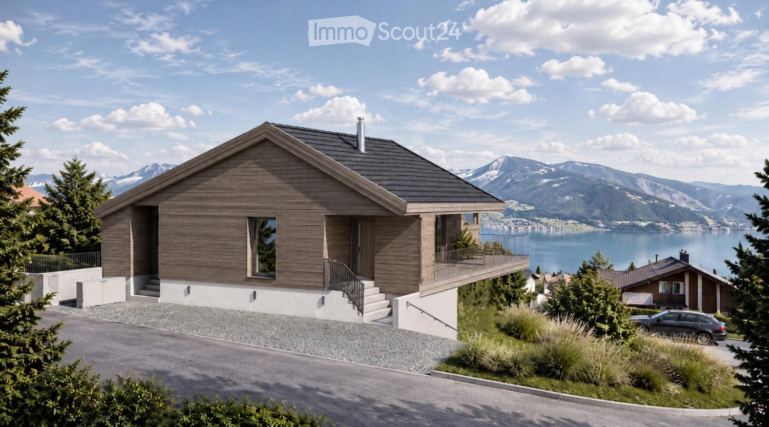 Modern two-story house with wooden facade, large windows, and a balcony overlooking a scenic lake and mountain view.