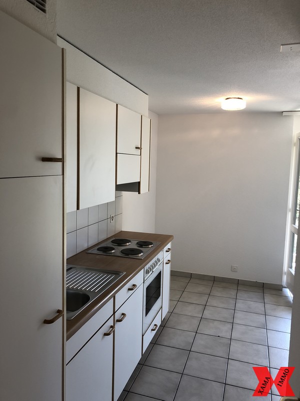 Modern kitchen, white cabinets, tiled floor, gas stove, sink, and oven.