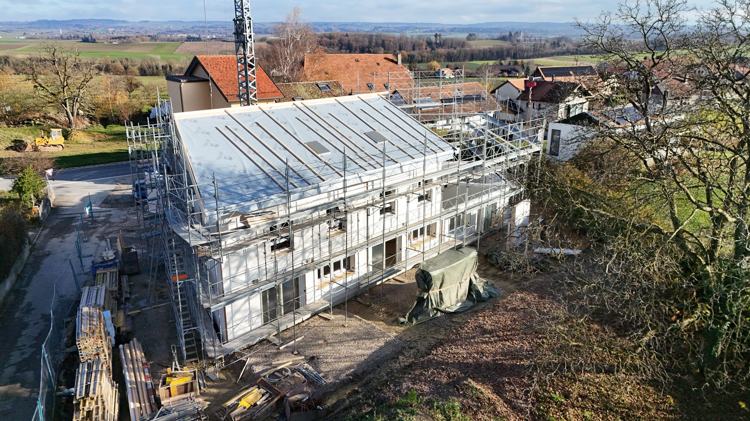 New house under construction, metal scaffolding, large windows, flat roof, bare trees