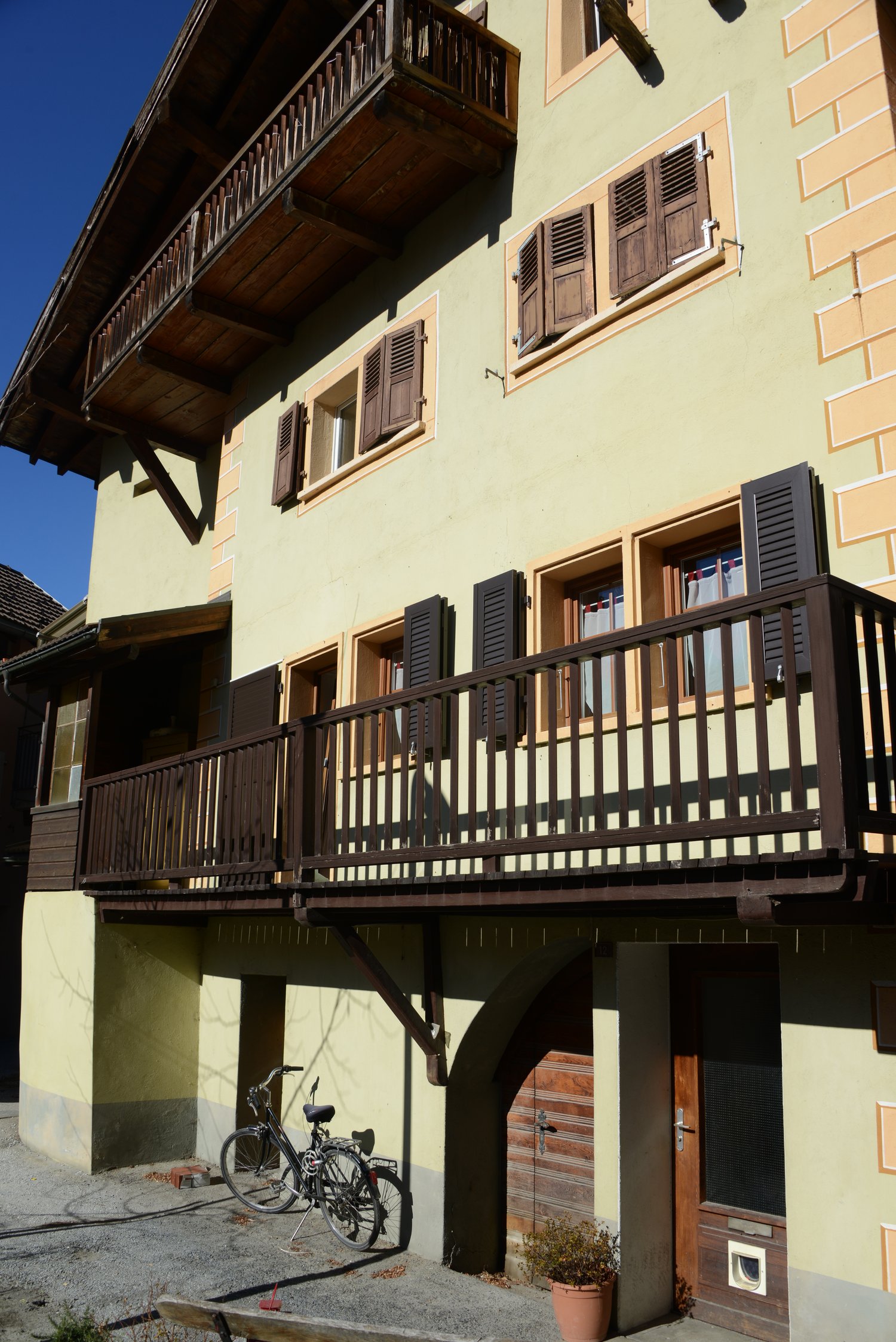 two balconies, wooden shutters, yellow painted walls, bicycles parked outside