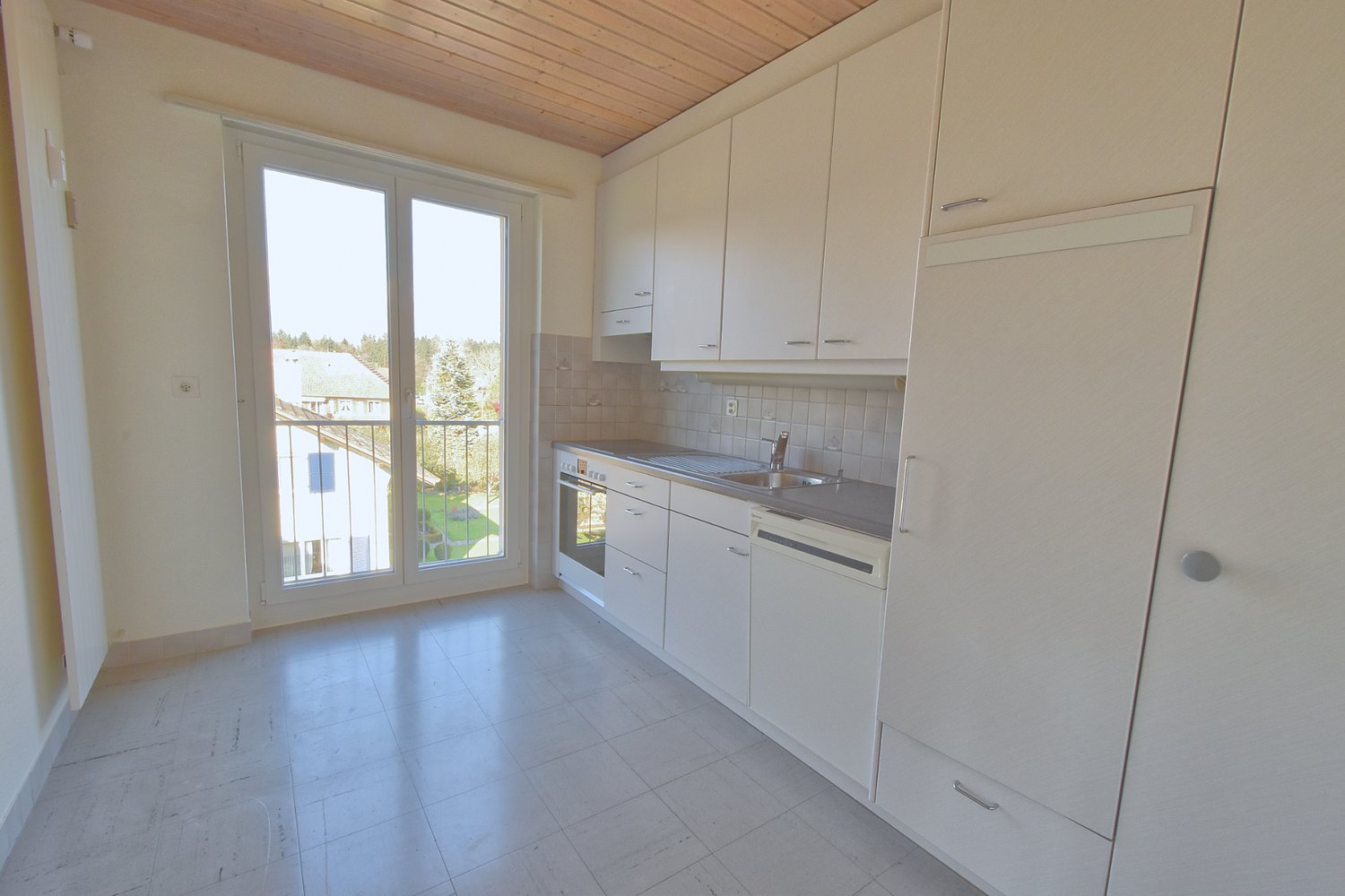 Empty kitchen with modern fittings, large window, dishwasher, washing machine, oven.