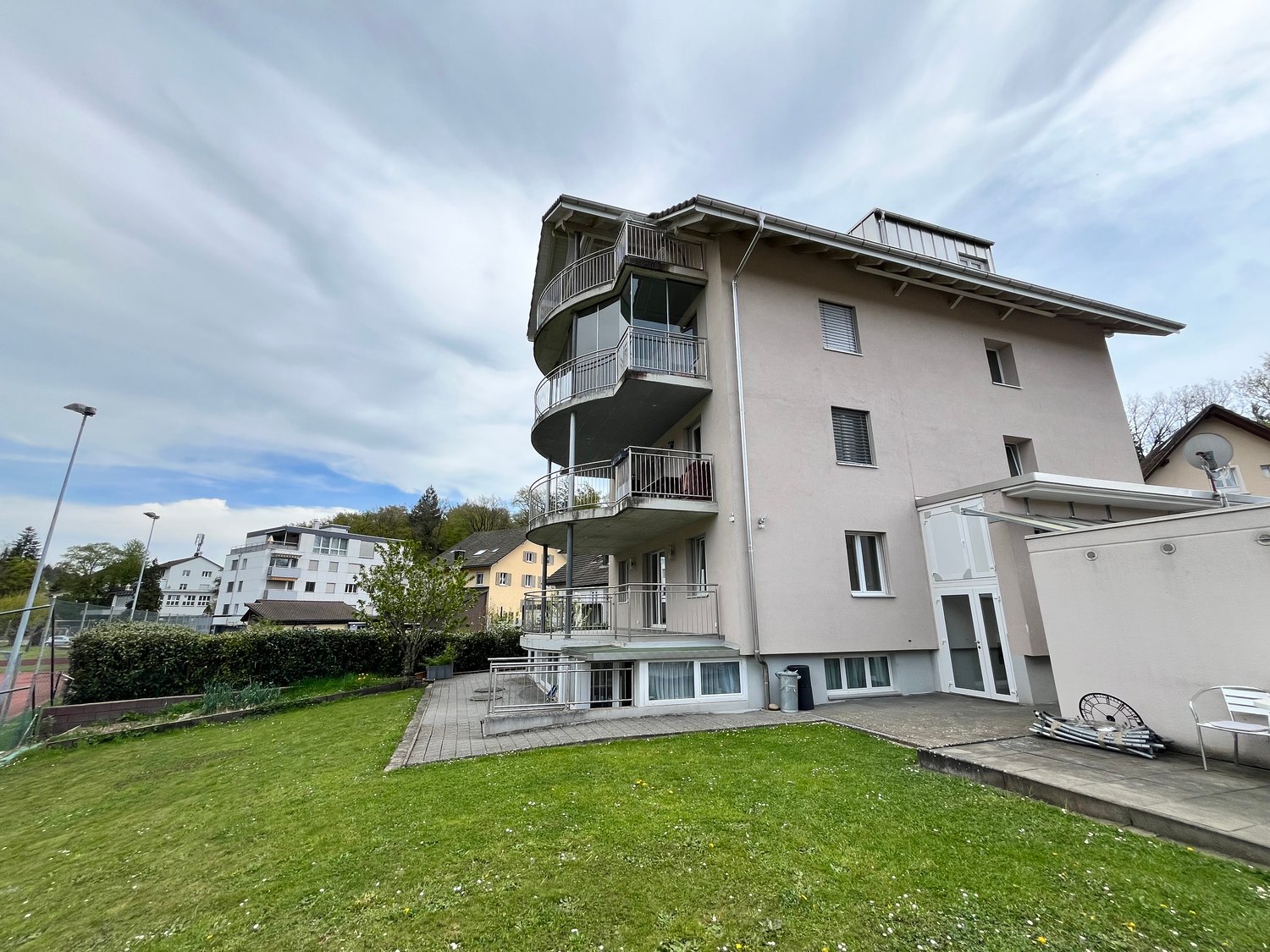 3 story building, balconies, large windows, garden, tennis court