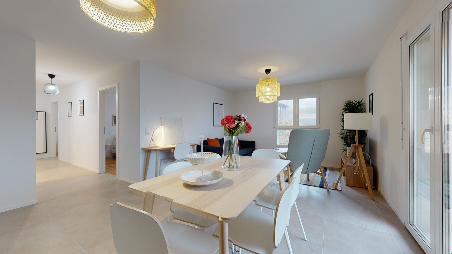 Dining room with a table, chairs, and a flower vase on the table. There is a lamp on the wall and a plant in the corner. The room has a sliding glass door leading to a balcony.