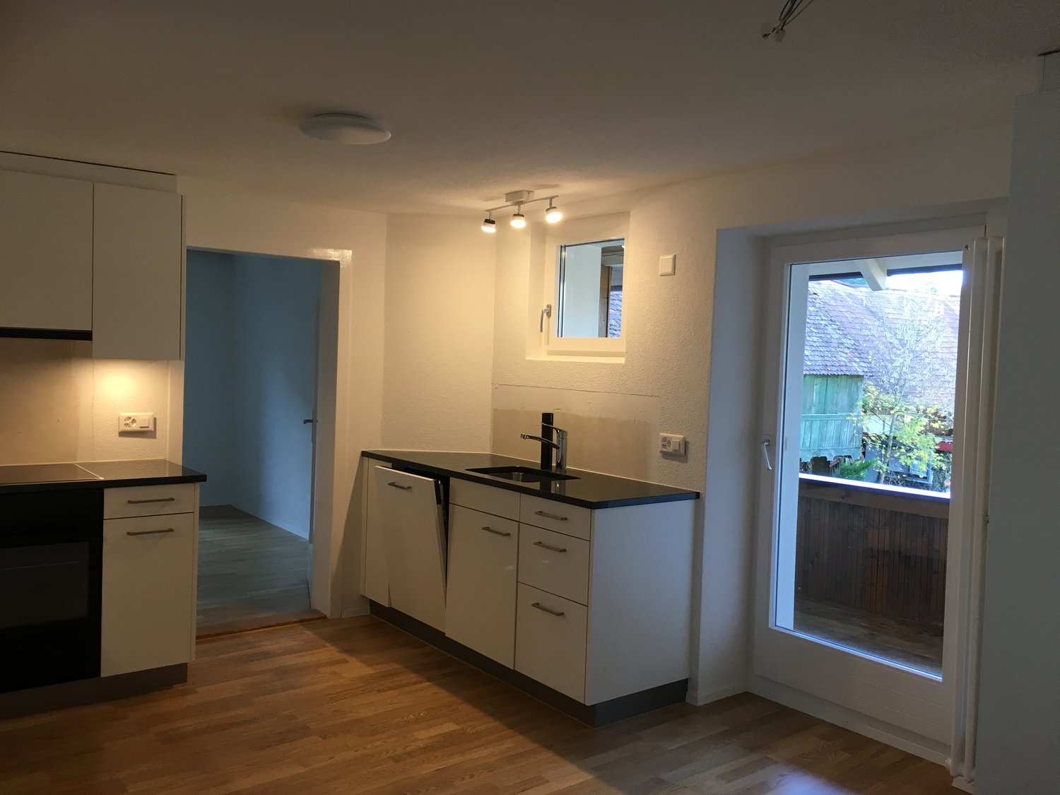 white cabinets, black countertop, sink, faucet, oven, balcony