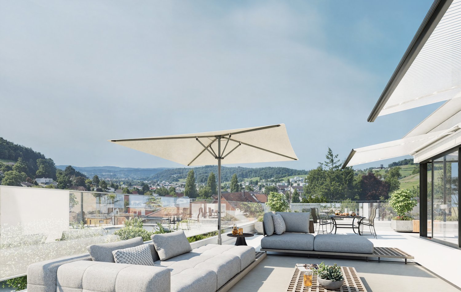 A large outdoor terrace with a large sofa, a desk with an umbrella, a glass wall, and a garden view.