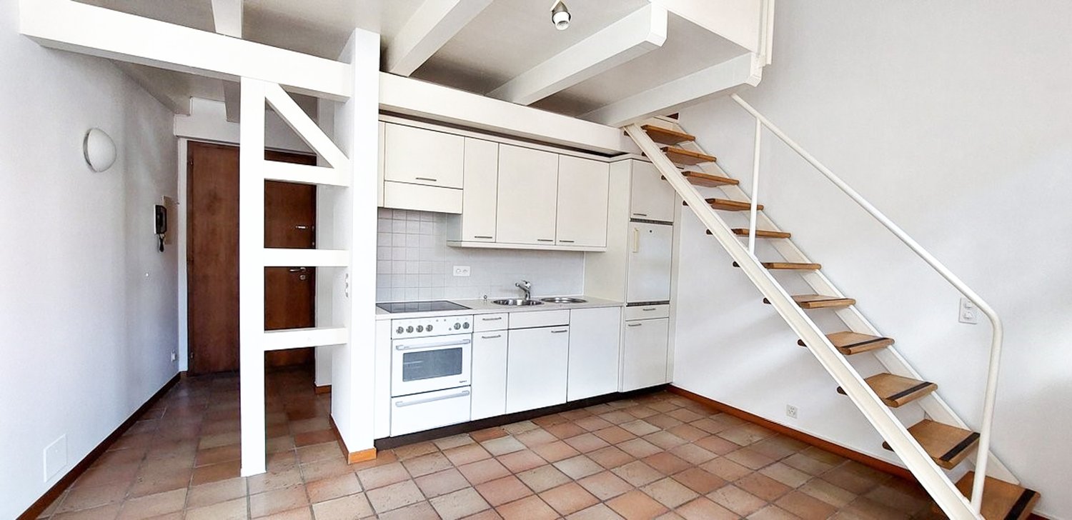 modern kitchen, white cabinets, tile flooring, staircase to upper level, stove, sink