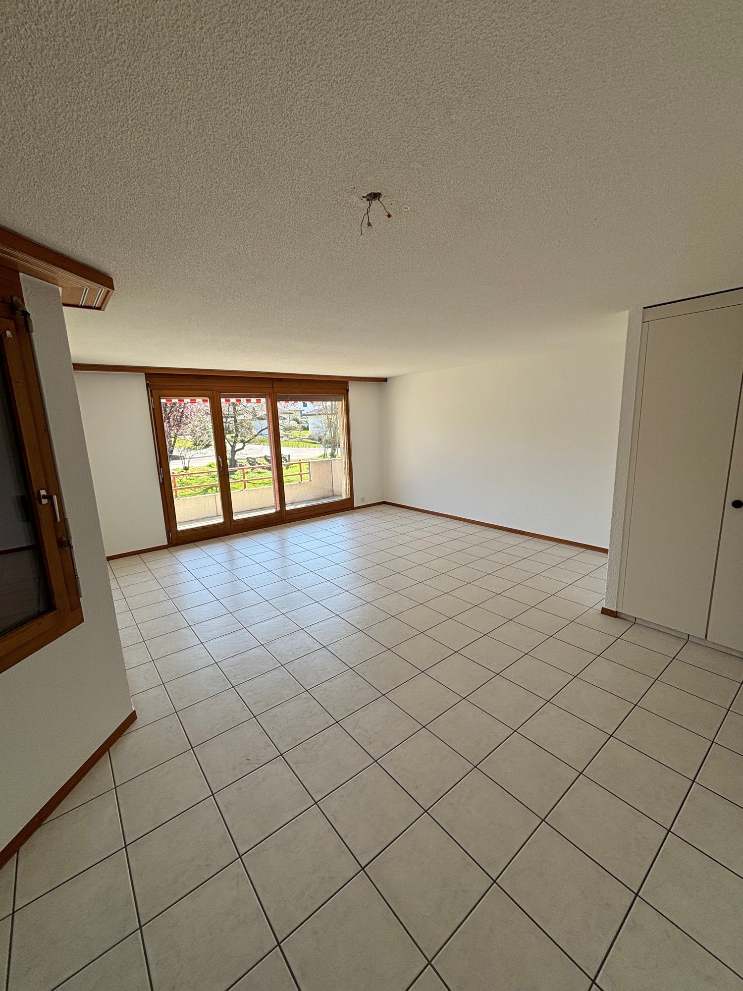 large empty room, large sliding windows, tiled floor, wooden doors