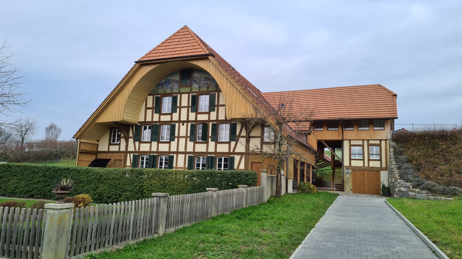 wooden house, red roof, arched entrance, large windows, elevated ground floor, garden, stone pathway