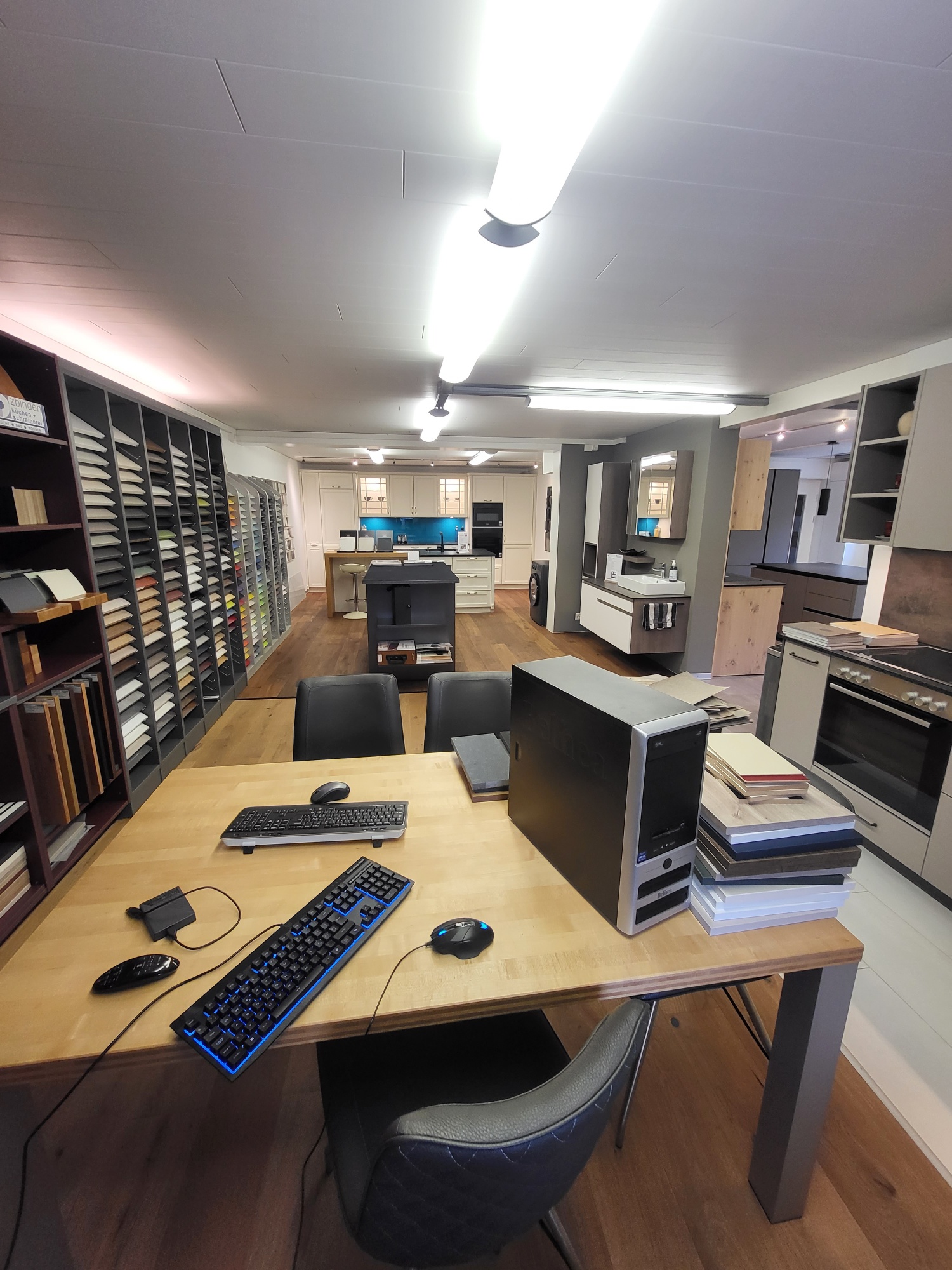A room with desks, computers, keyboards, mice, and chairs.