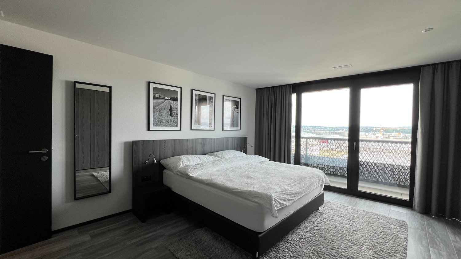 Modern design bedroom with bed, nightstand, mirror, wall art, sliding doors, and balcony