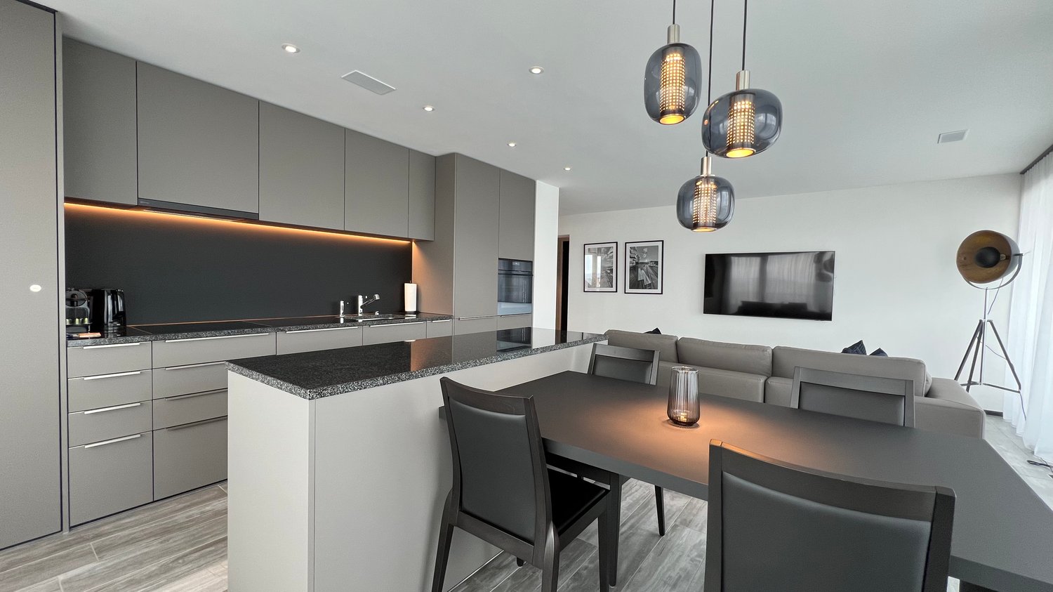 kitchen, dining area, living room, modern style, neutral colors, hardwood floors, built-in cabinets, granite countertop, LED strip lights, LED pendant lights, flat screen TV, large sectional sofa, coffee table, floor lamp