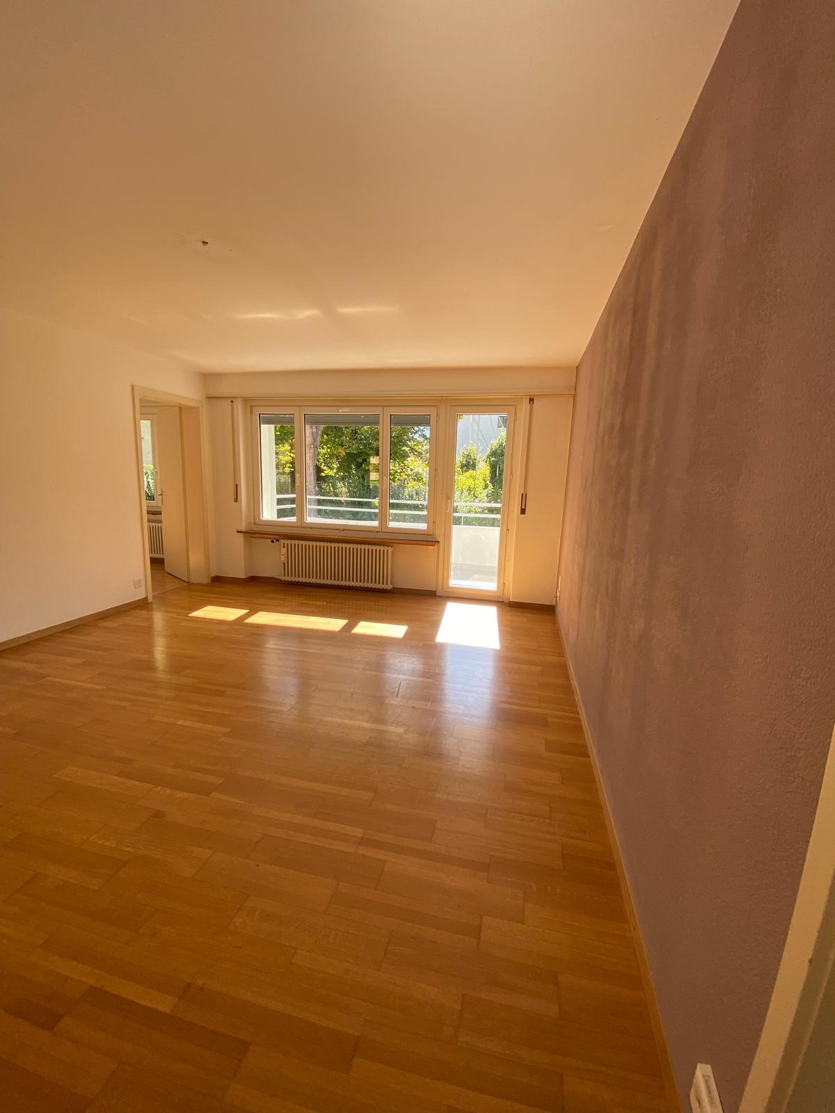 empty room, wooden floor, sliding glass doors, balcony, white walls, white ceiling, radiator