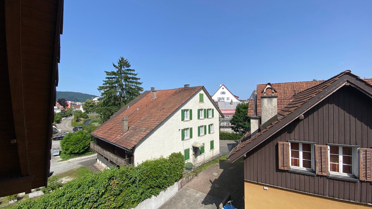 2 story house, red tiled roof, white walls, green window shutters, raised ground floor