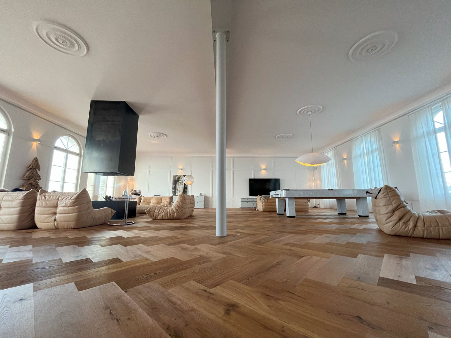 modern living room, hardwood floors, large windows, modern furniture, central column, suspended lights