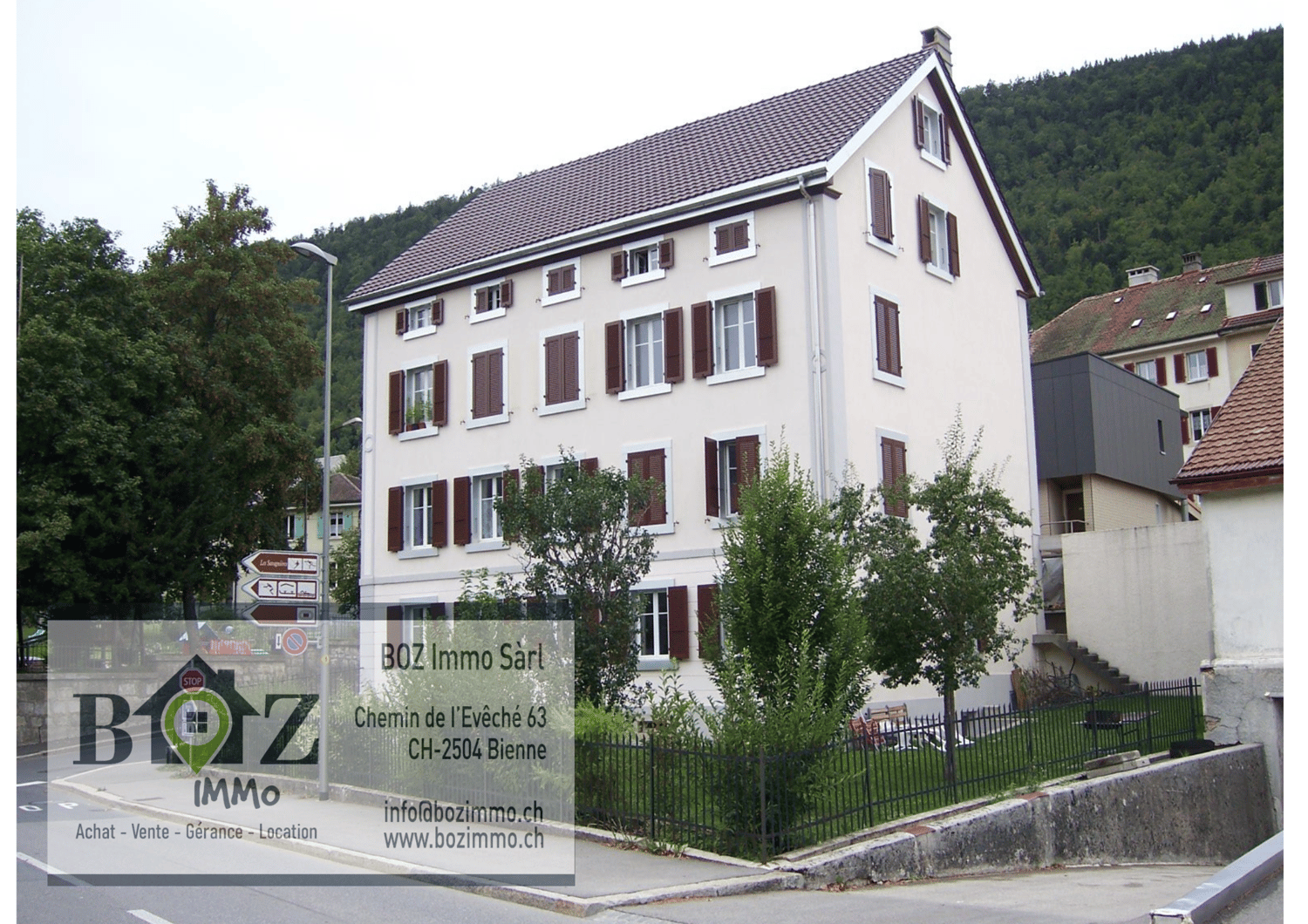 Apartment building, white painted walls, brown roof, large windows, balcony, small green garden