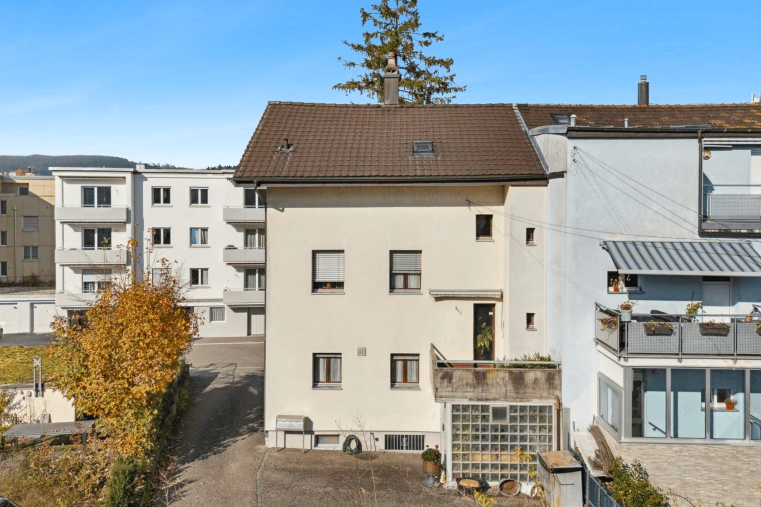 white apartment building, balconies, brown roof, multiple windows, chimneys