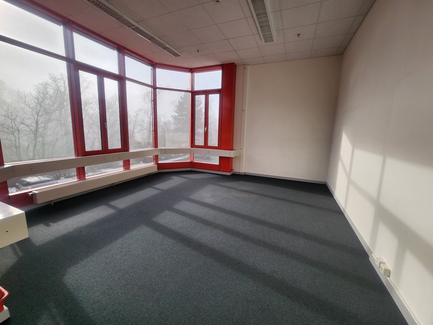 Empty room with large windows and grey carpet.