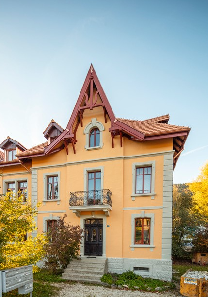2 story house, yellow exterior, red roof, balcony, multiple windows, front door, steps leading to entrance