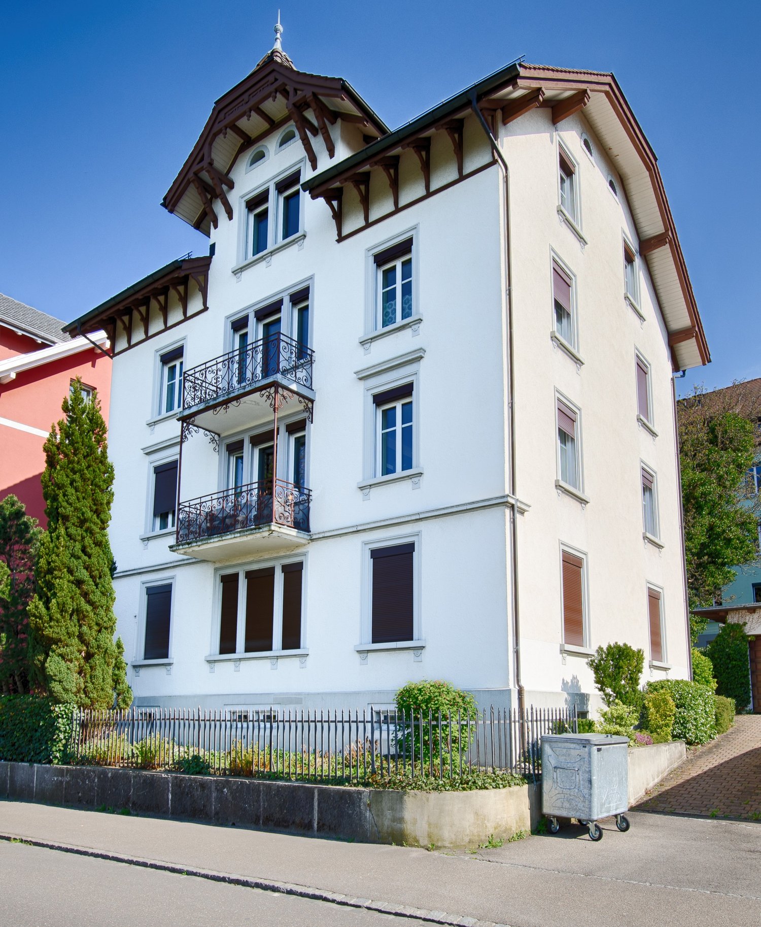 white house with multiple floors, balcony on the first floor