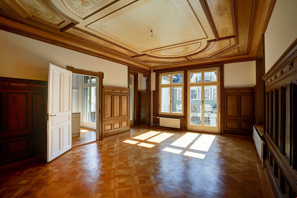 Parquet floor, wooden paneling, large glass windows, ornate ceiling, open door