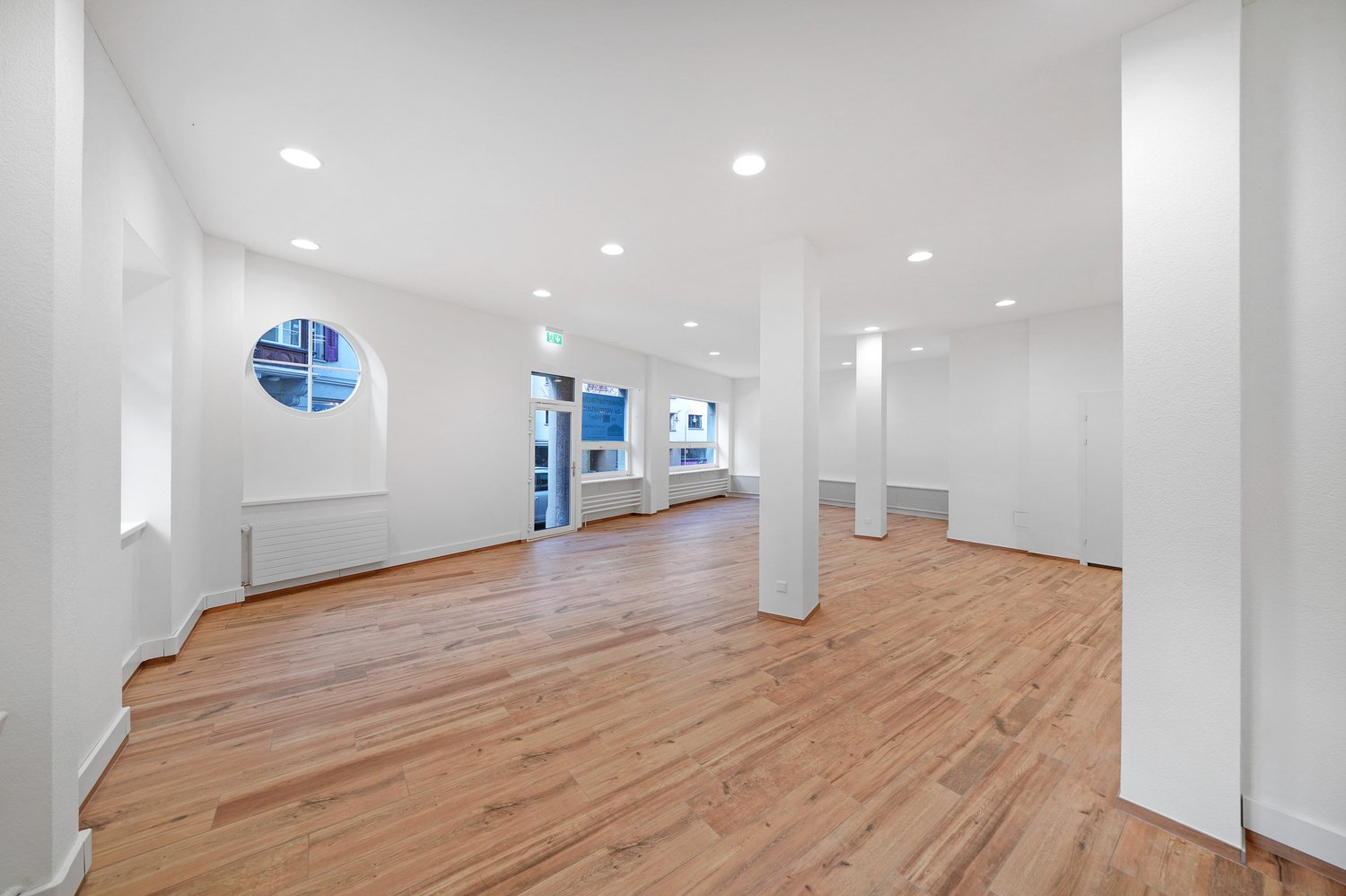 empty room, wooden floor, white walls, round window, glass door, radiators