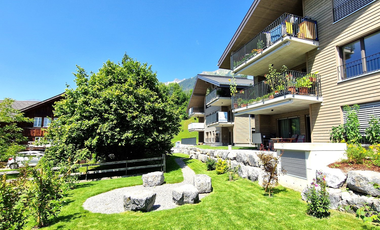 modern house, balconies, large windows, plants, rocks, greenery, pathway, mountains in the distance