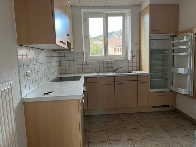 modern kitchen with two sinks, double black square kitchen counter, large open refrigerator, wooden cupboards, tiled floor, large window