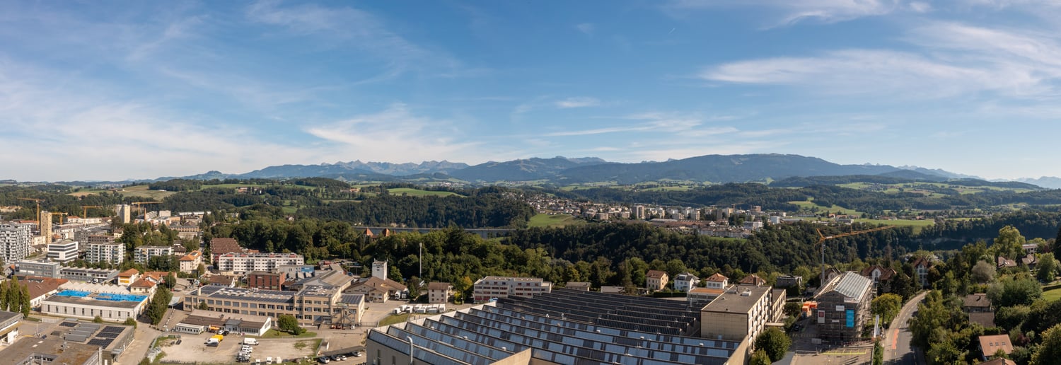 city with mountains in the background, many buildings, some trees