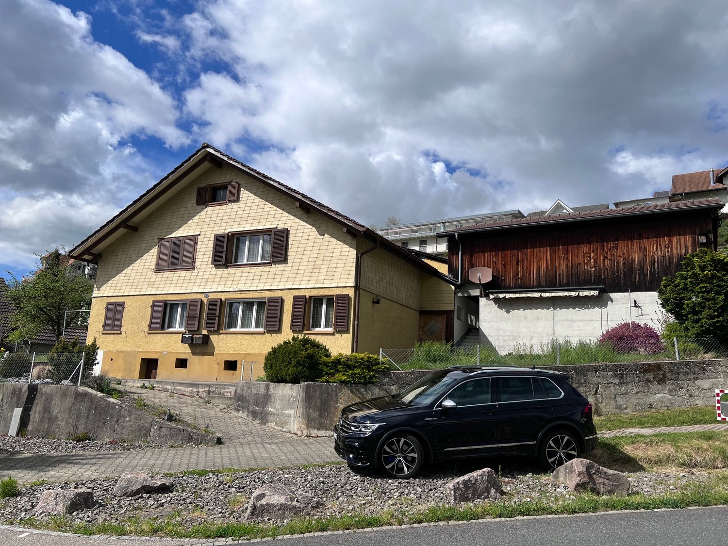 Two story yellow house, brown windows, brown roof, parking in front