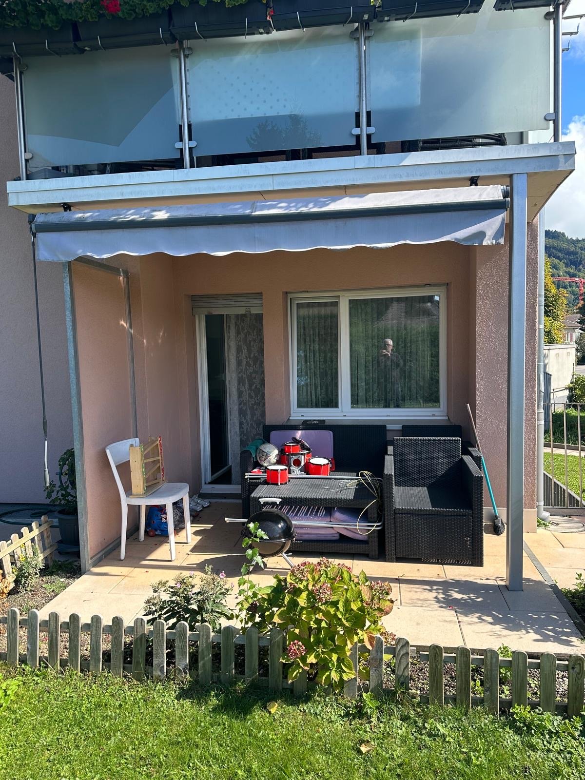 Covered balcony, garden furniture, plants, wooden fence, open balcony space above