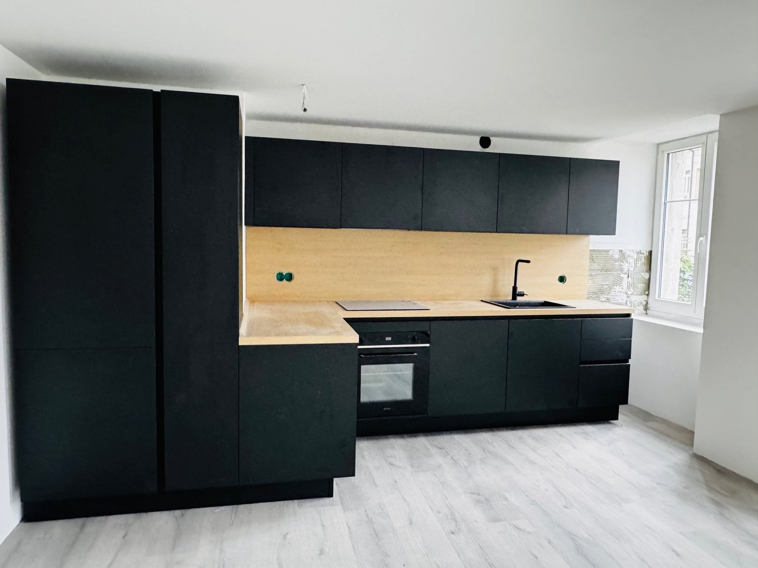 modern kitchen, black cabinets, wooden countertop, stainless steel sink, built-in oven and stove