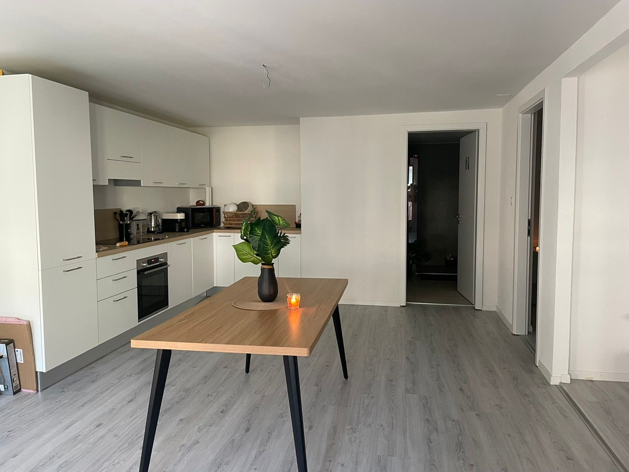 white cabinetry, grey floors, wooden table, white walls, open door