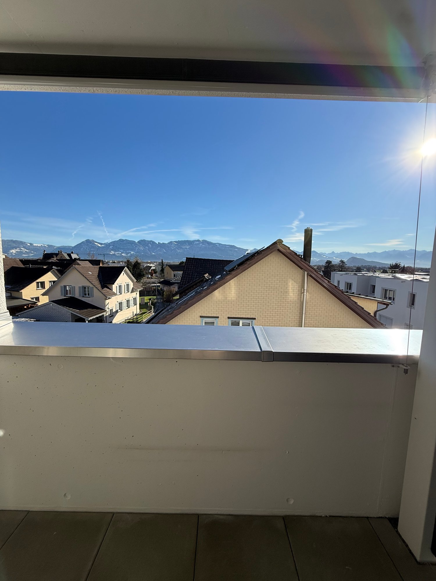 Tiled floor, glass fence, panoramic city view, mountains in the background