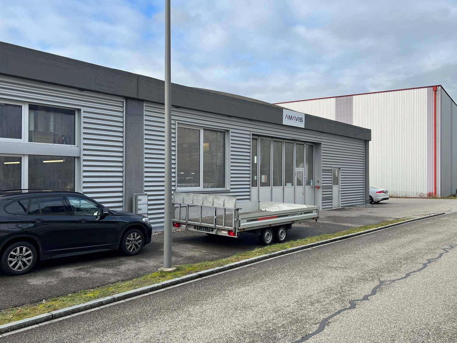 grey building with sign AMAVIS, 3 cars parked in front